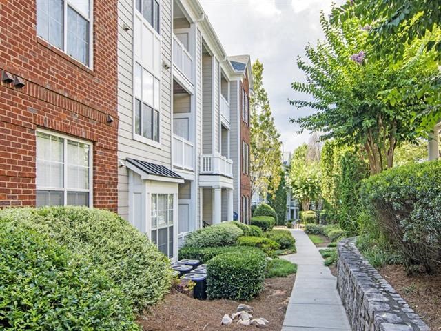 a sidewalk in front of a brick apartment building