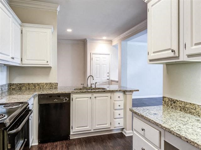 a kitchen with white cabinets and a stove and a sink