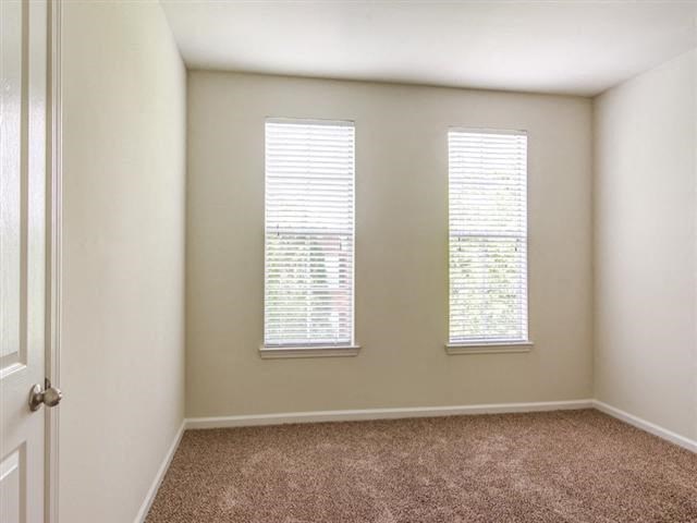 an empty room with three windows and a door