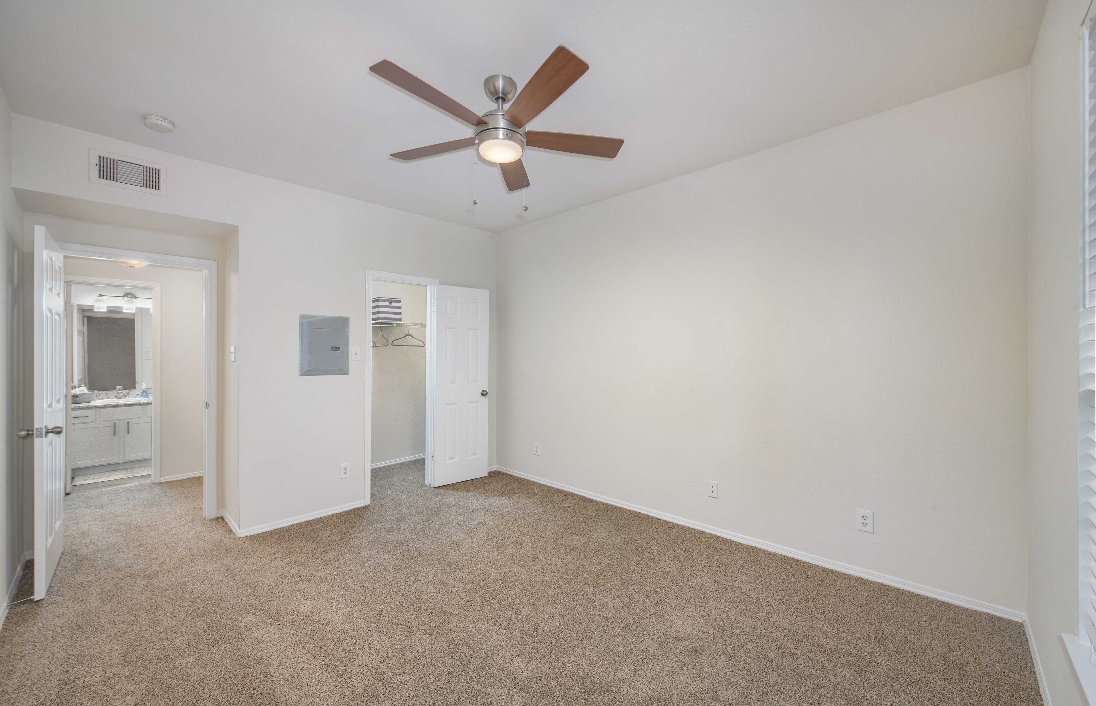 a spacious living room with carpet and a ceiling fan