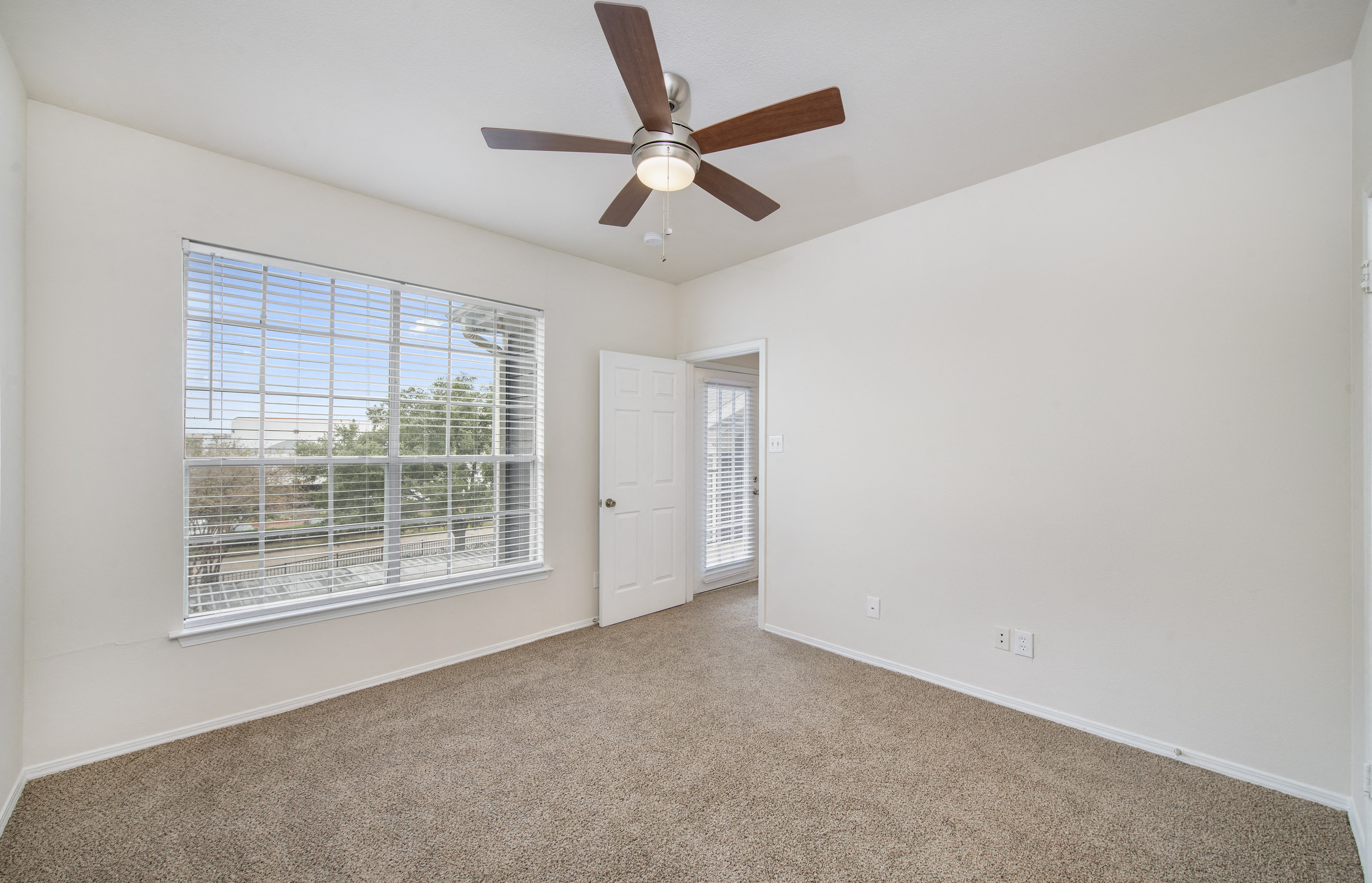 an empty living room with a ceiling fan and a window