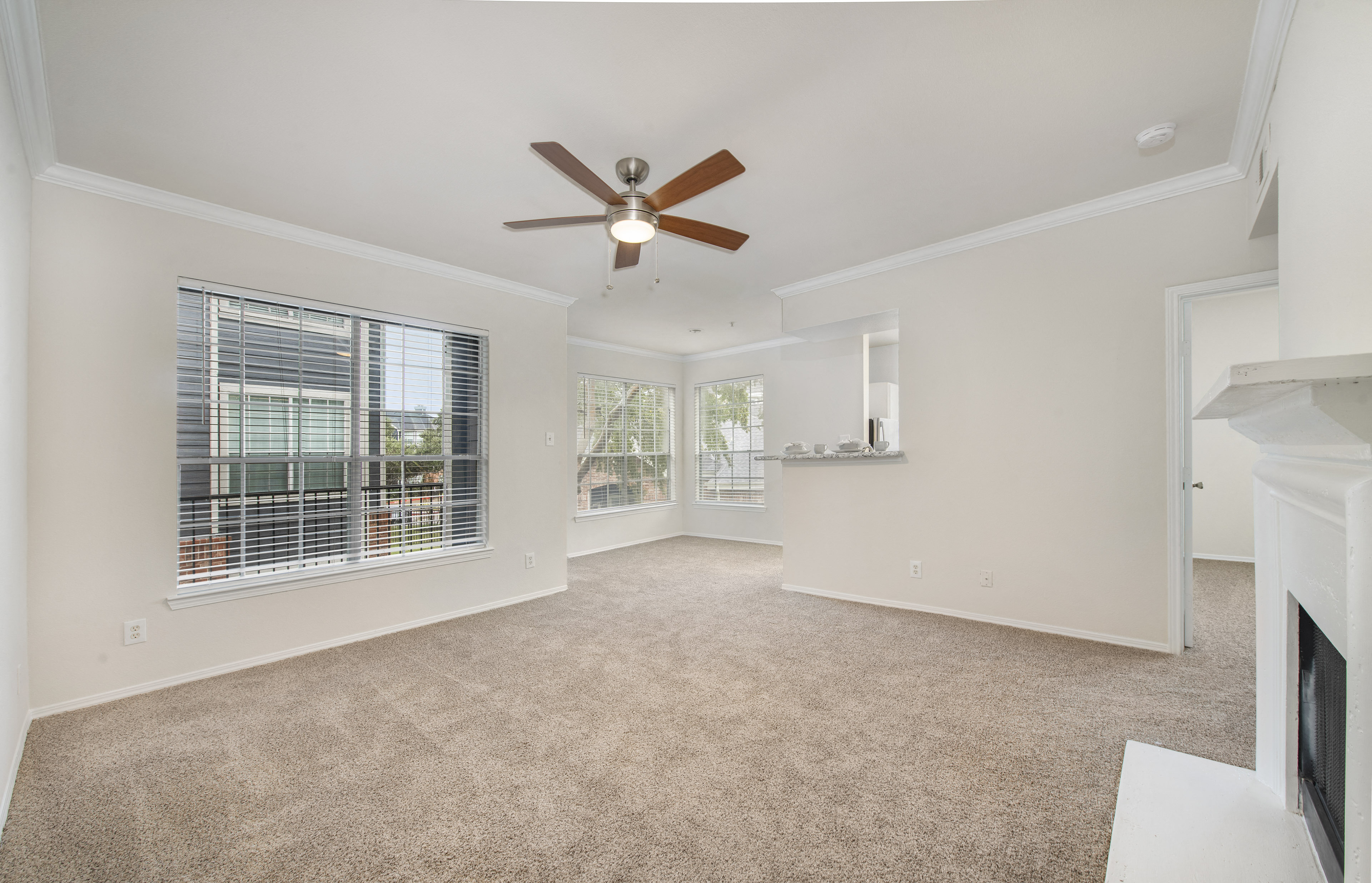 an empty living room with a ceiling fan and a window