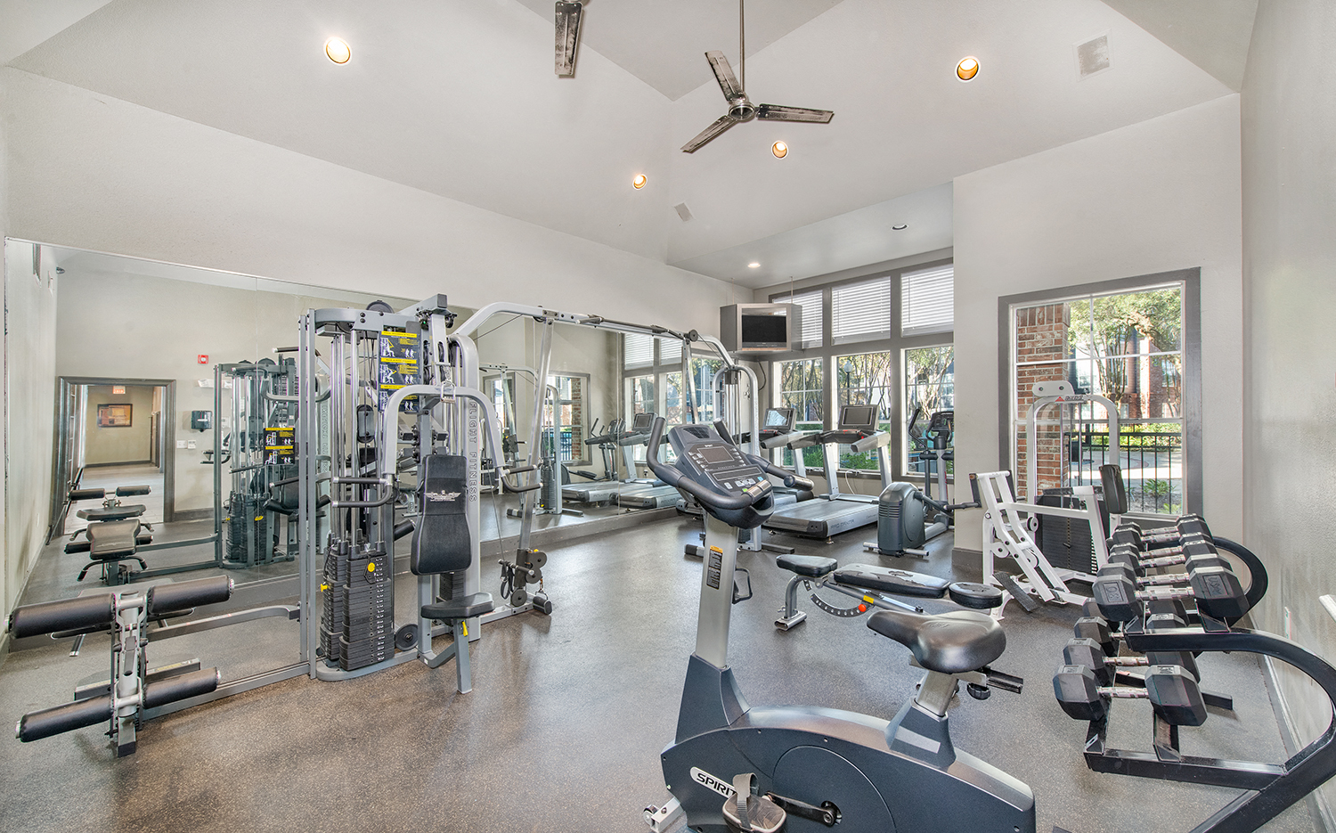 a gym with weights and cardio equipment and windows