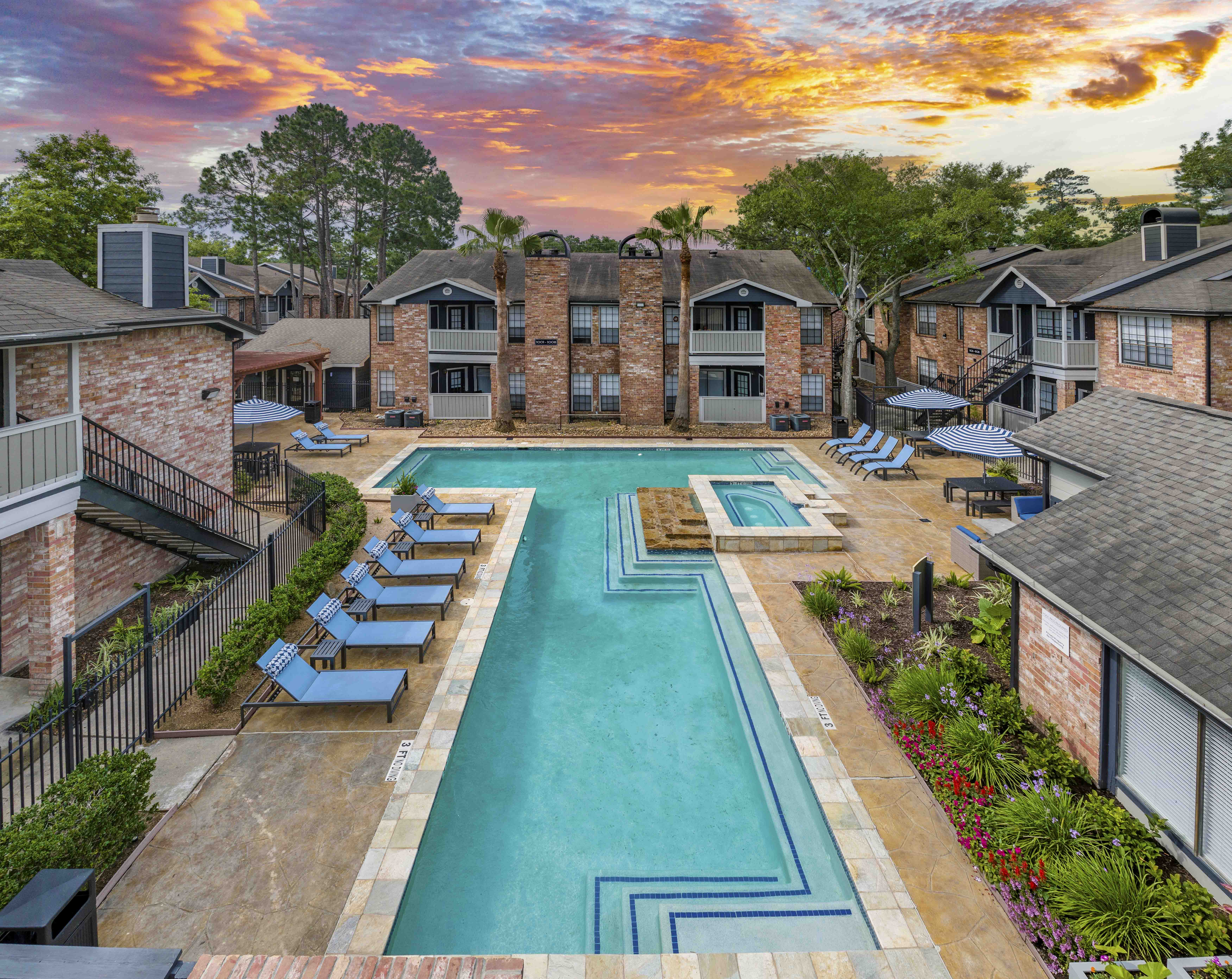 an aerial view of an apartment complex with a pool and lounge chairs