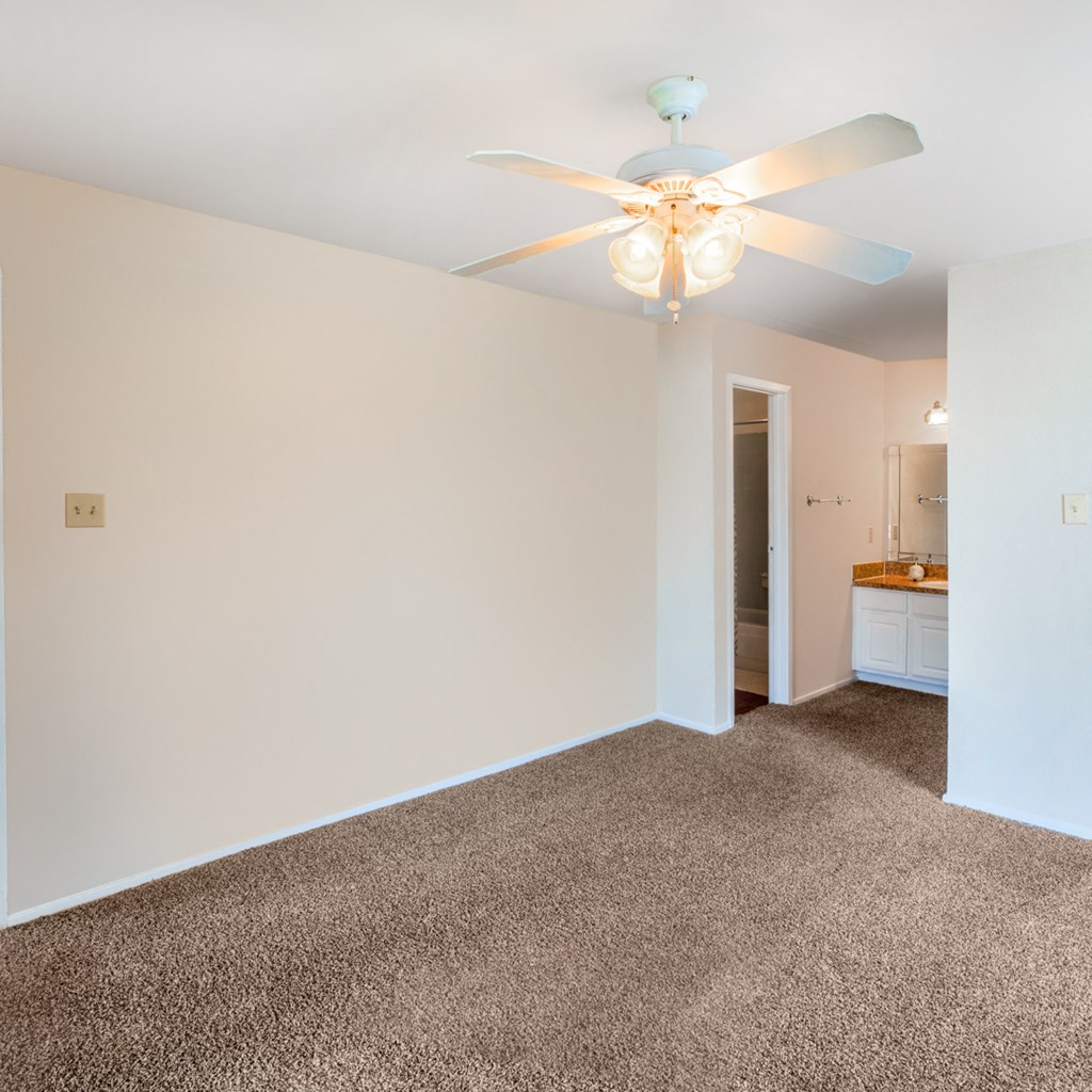a living room with white walls and a ceiling fan