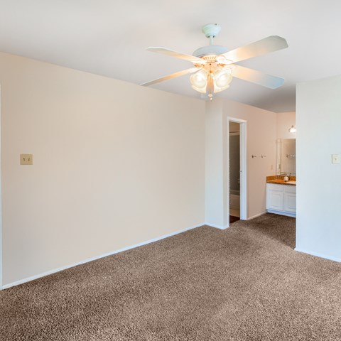 a living room with white walls and a ceiling fan