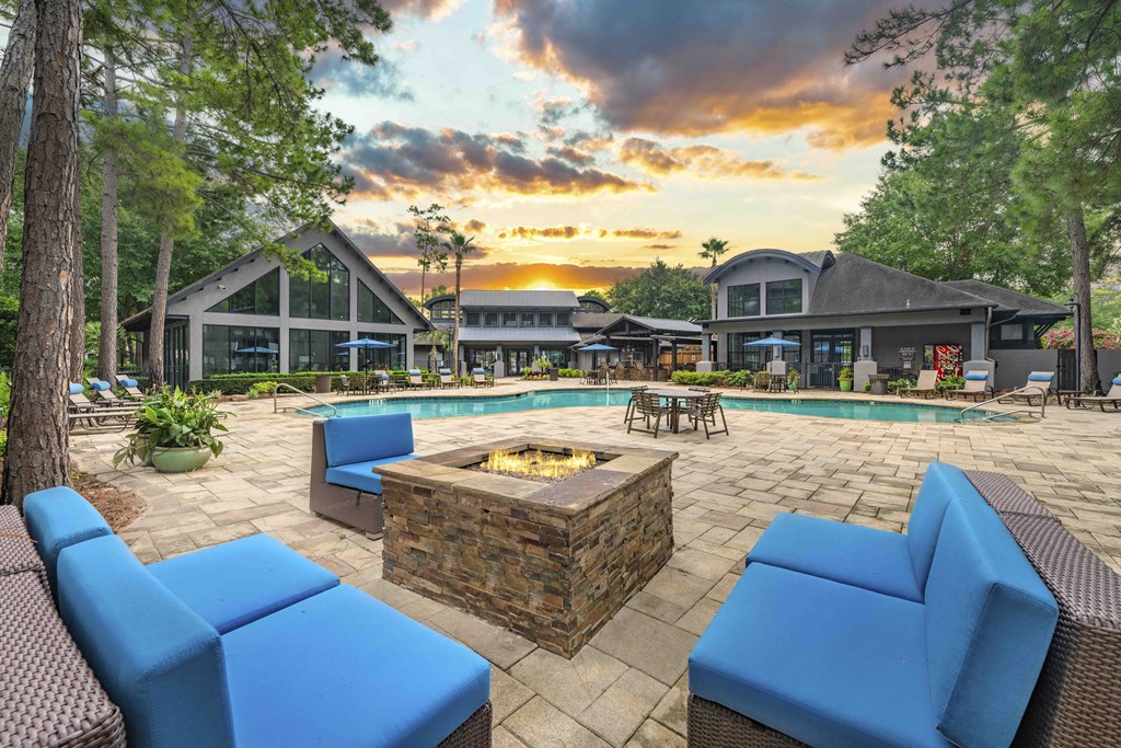 a patio with blue couches and a fire pit and a pool