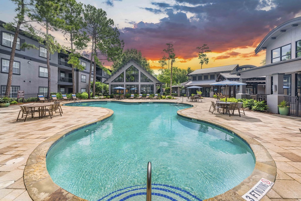 a swimming pool with a sunset in the background at an apartment complex