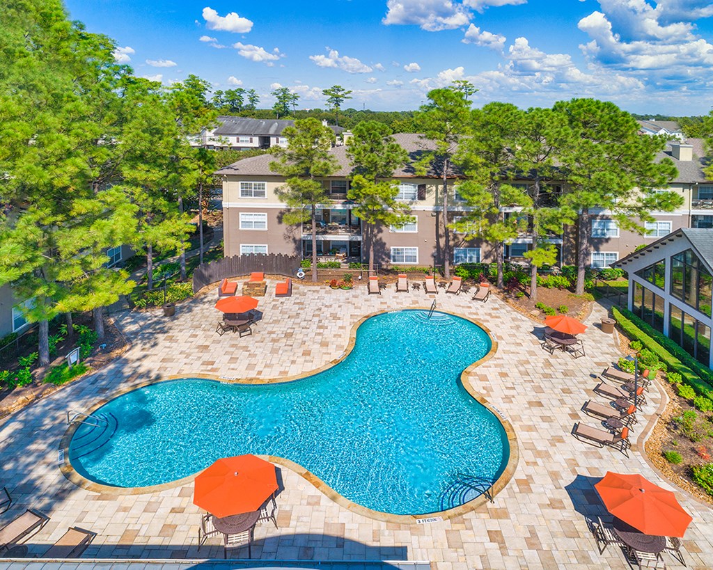 an aerial view of a swimming pool and patio with umbrellas