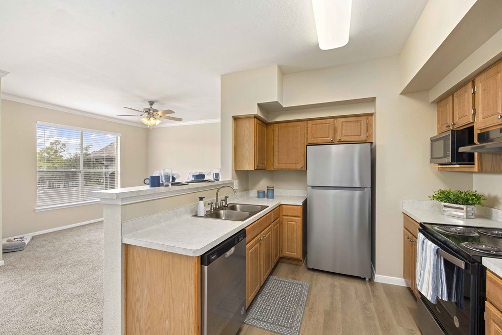 A kitchen with wooden cabinets and a stainless steel refrigerator.