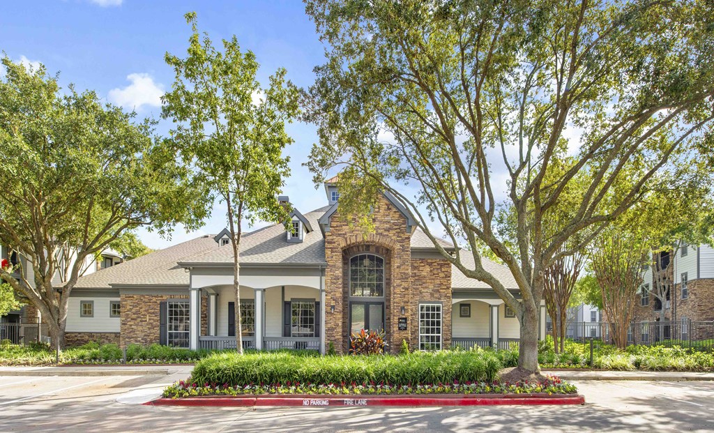 A house with a red brick facade and a large tree in front.