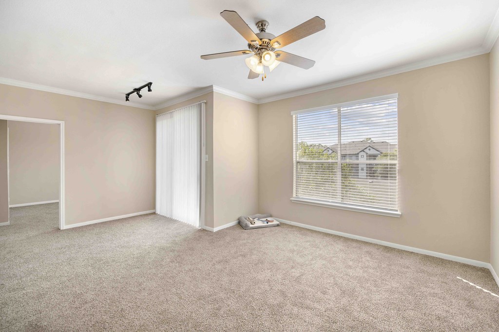A room with a ceiling fan and a window with blinds.