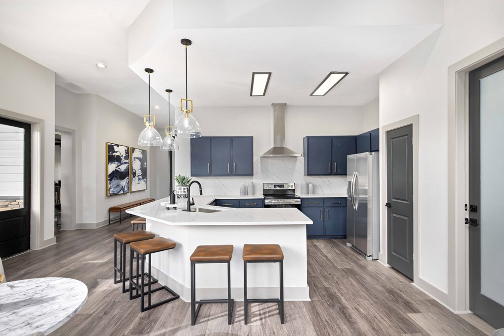 A modern kitchen with a white island and dark wood floors.