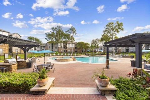 A pool area with a table and chairs and umbrellas.