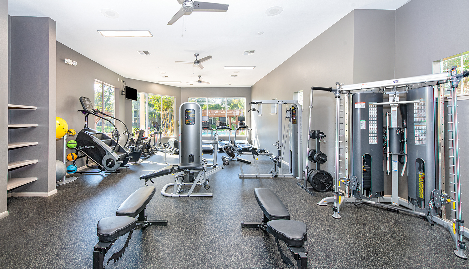 a gym with weights and cardio machines and a window