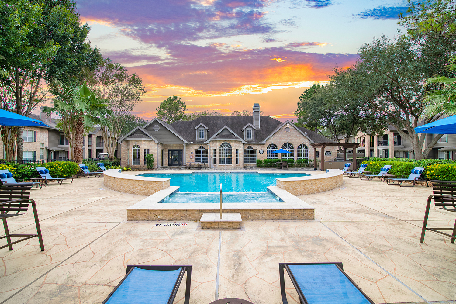 a swimming pool with chairs and a house in the background