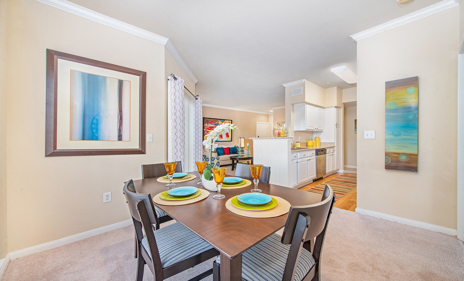 a dining area with a table and chairs and a kitchen in the background