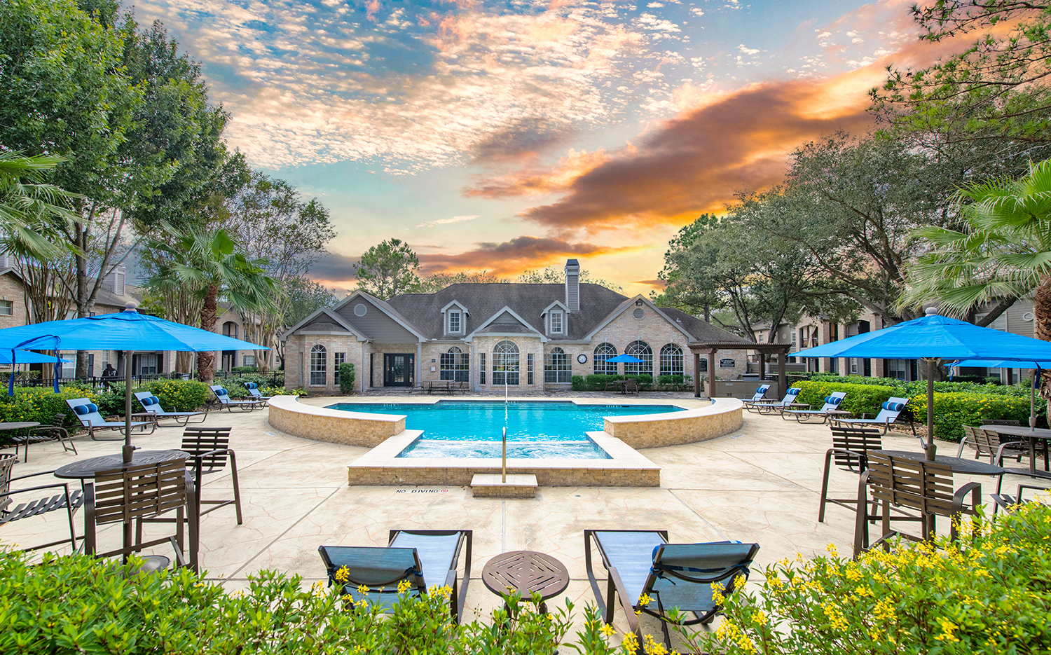 an outdoor pool with chairs and umbrellas and a house in the background