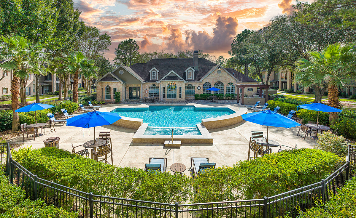 an outdoor pool with umbrellas and chairs and a house with a swimming pool
