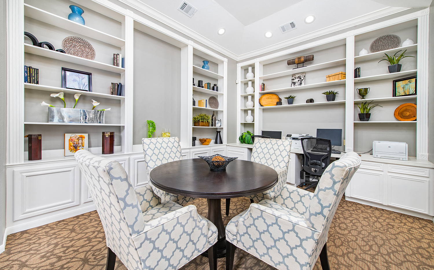 a living room with white shelves and a table and chairs