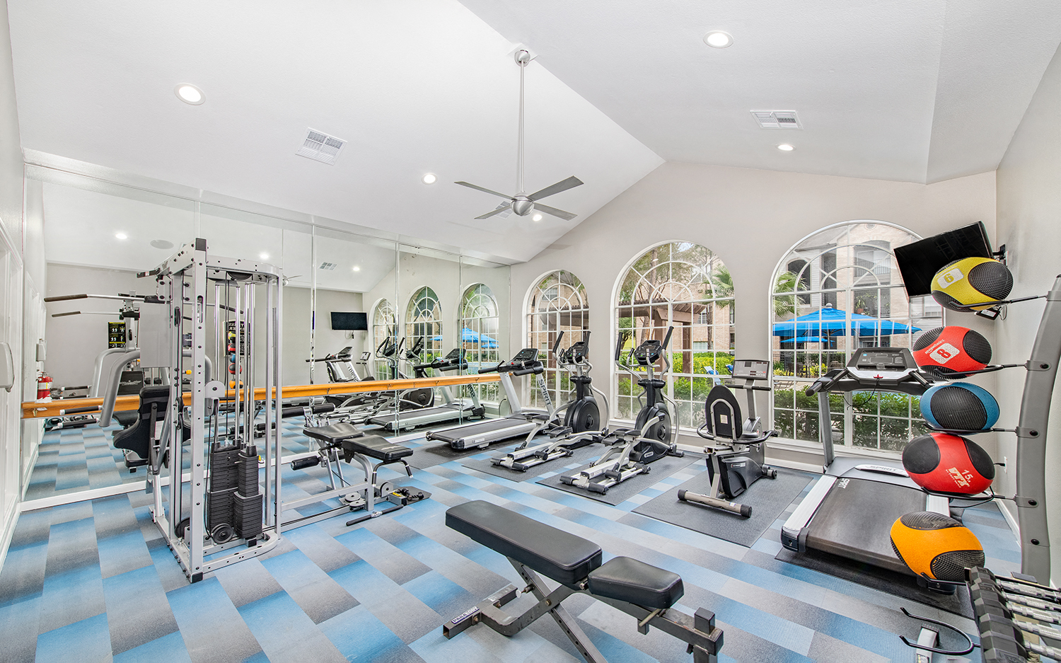 a gym with cardio machines and weights on a blue and white checkered floor