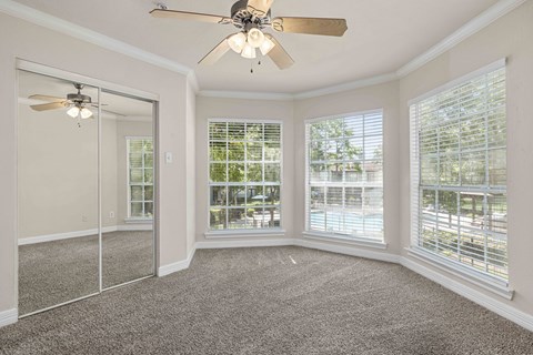 a living room with three windows and a ceiling fan
