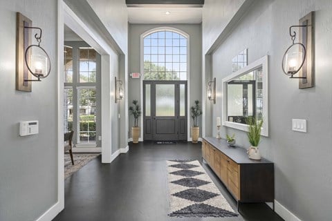 the front door of a house with a large window and a hallway with a cabinet