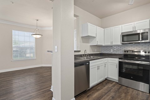 an empty kitchen with white cabinets and stainless steel appliances