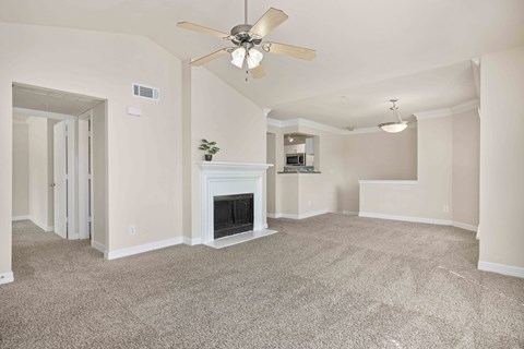 an empty living room with a ceiling fan and a fireplace