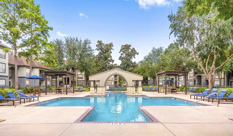 a resort style pool with lounge chairs around it and trees