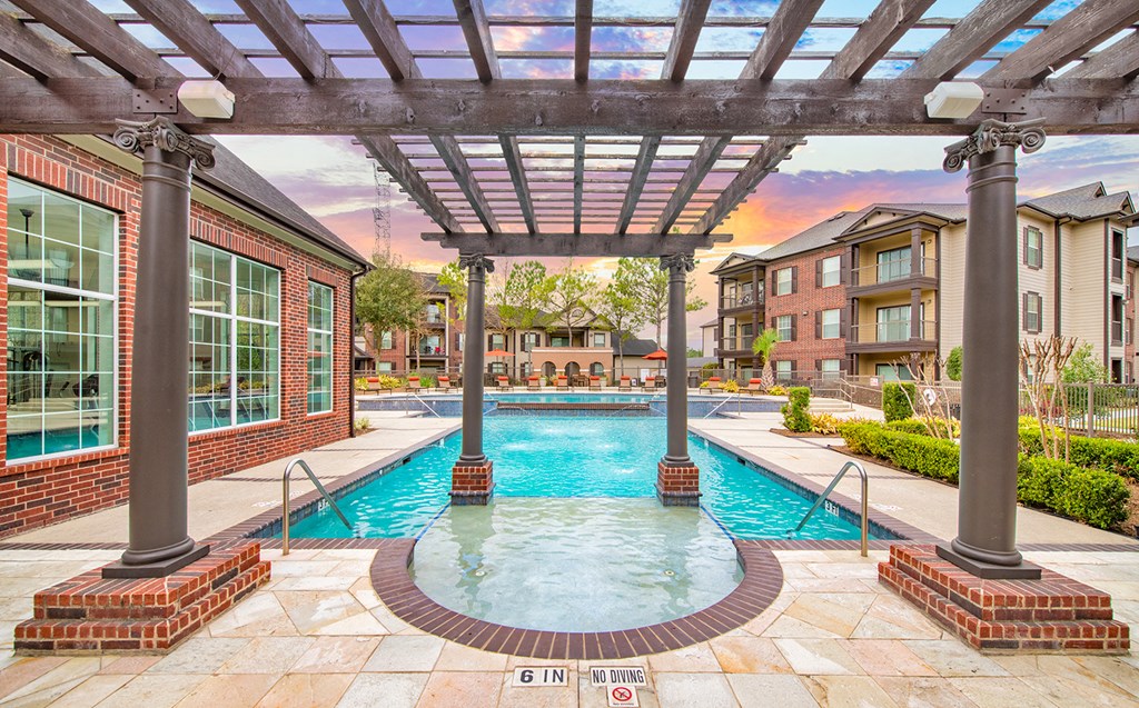 a swimming pool with a brick building and a pergola