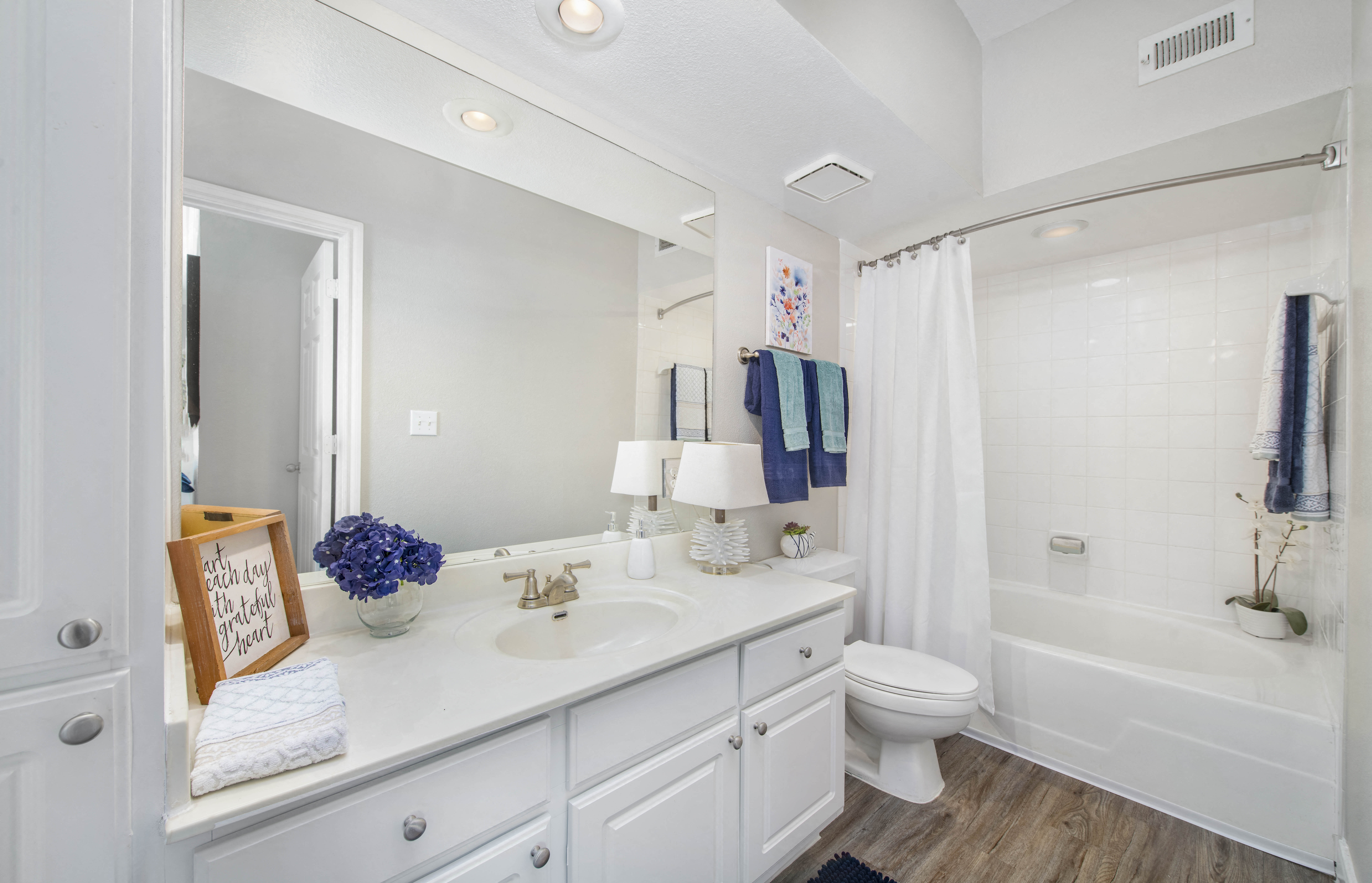 a white bathroom with a large mirror and a toilet and a shower