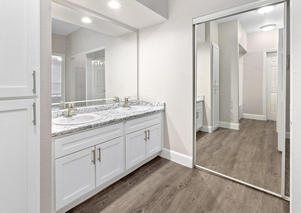 A bathroom with a large mirror and wooden floors.