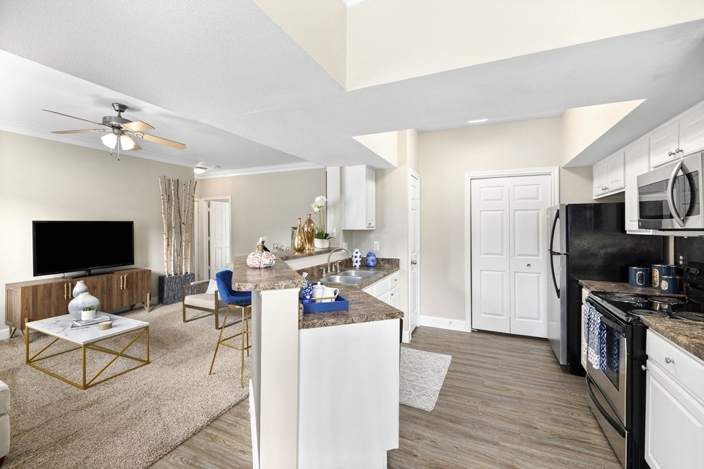 A modern kitchen with white cabinets and a black stove top oven.