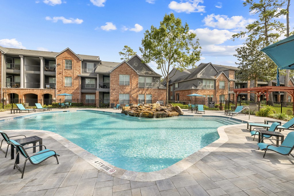 A large outdoor swimming pool surrounded by lounge chairs and buildings.