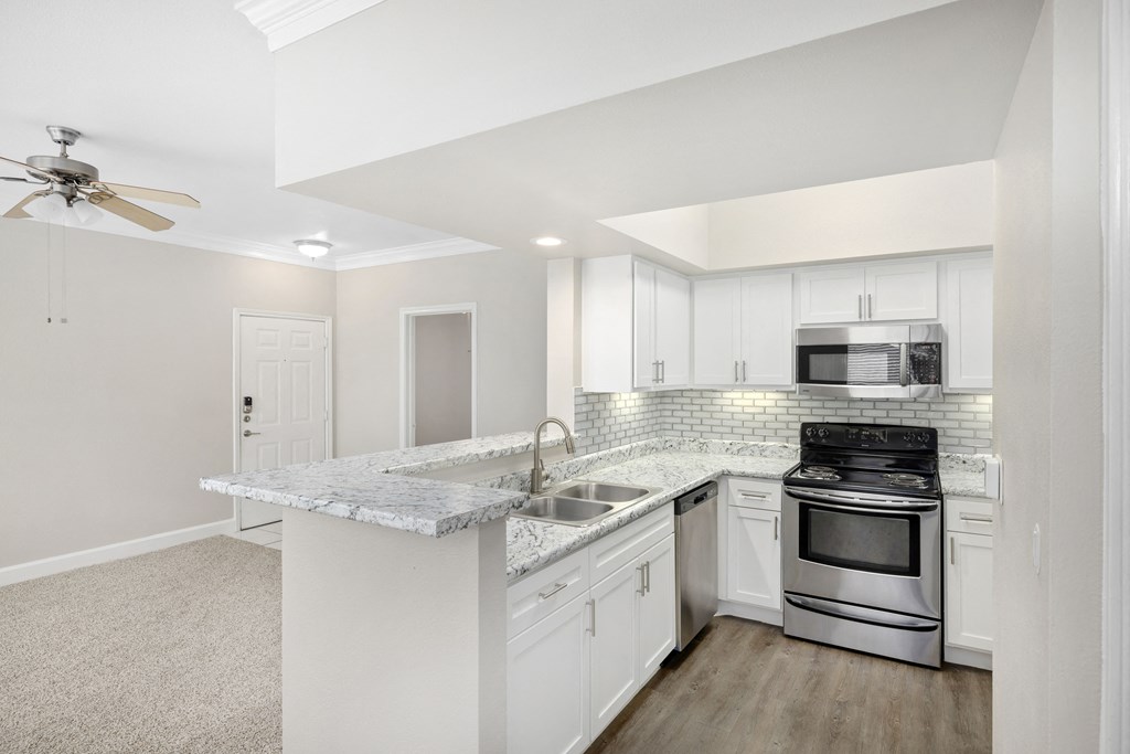 A kitchen with a marble countertop and stainless steel appliances.