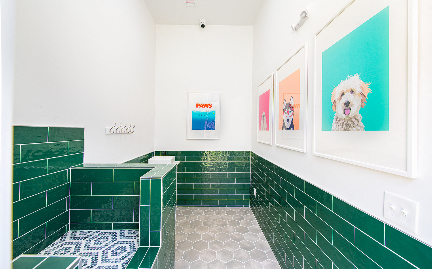 a bathroom with green tile and pictures of a dog
