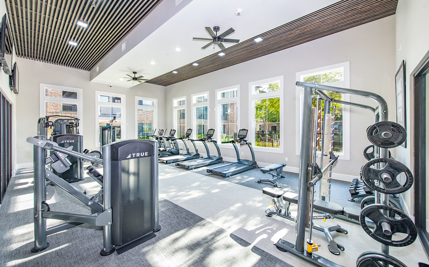 a gym with cardio equipment and windows at the district at highland village apartments