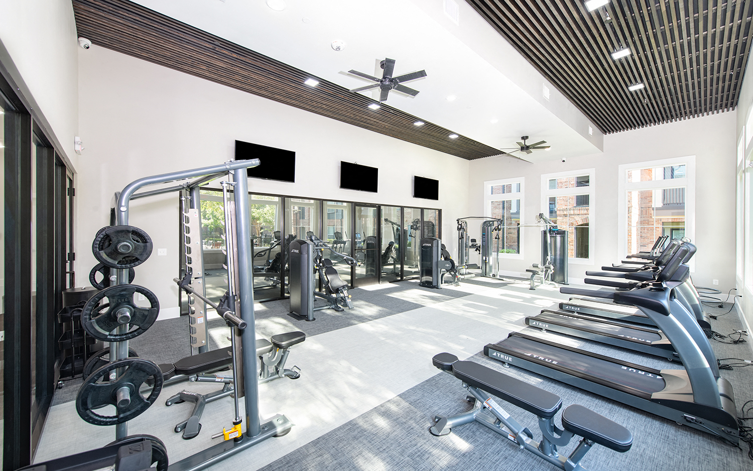 a gym with cardio equipment and windows in a building