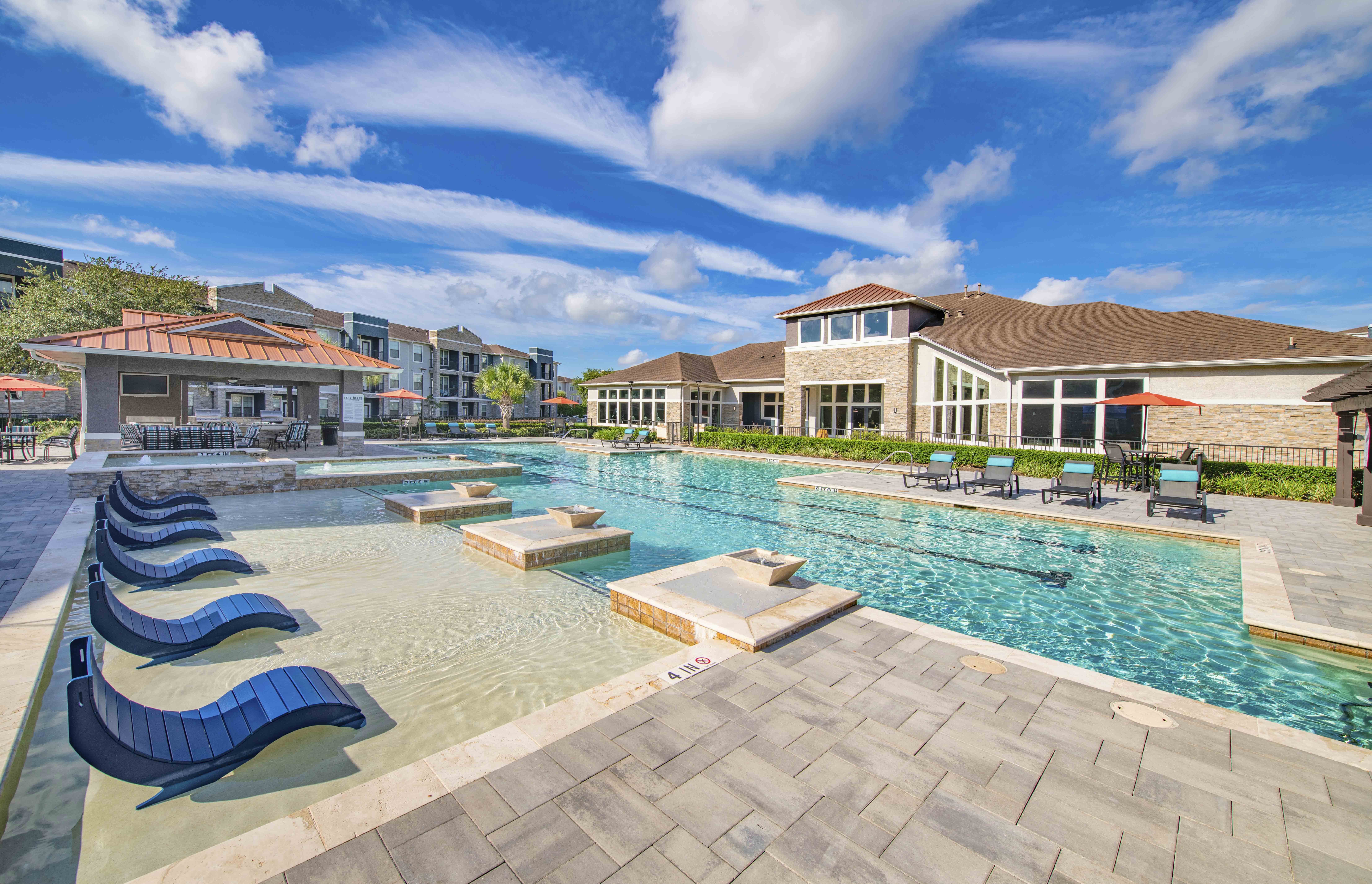 a swimming pool with lounge chairs and a building in the background