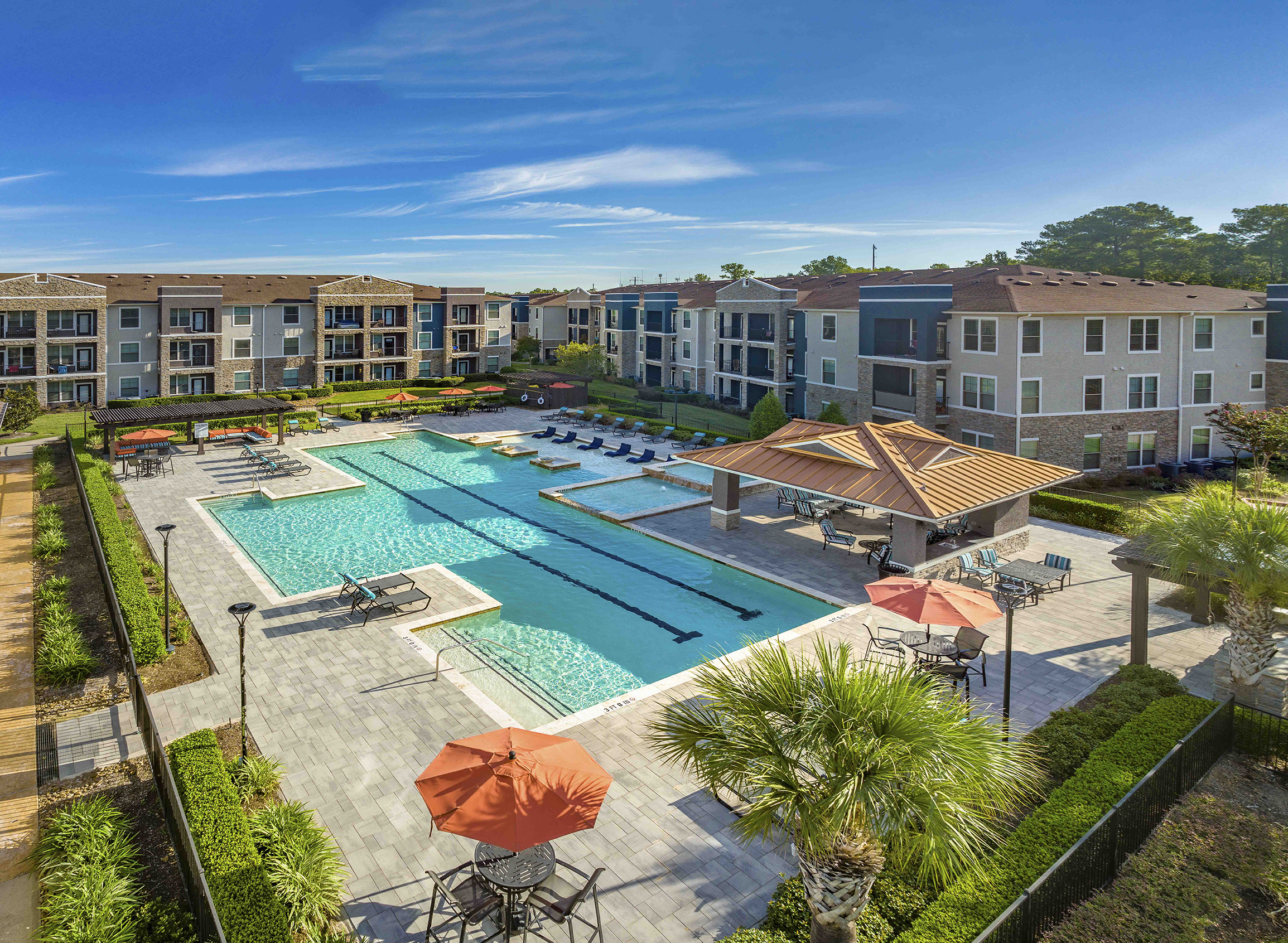 an aerial view of an outdoor pool with umbrellas and buildings