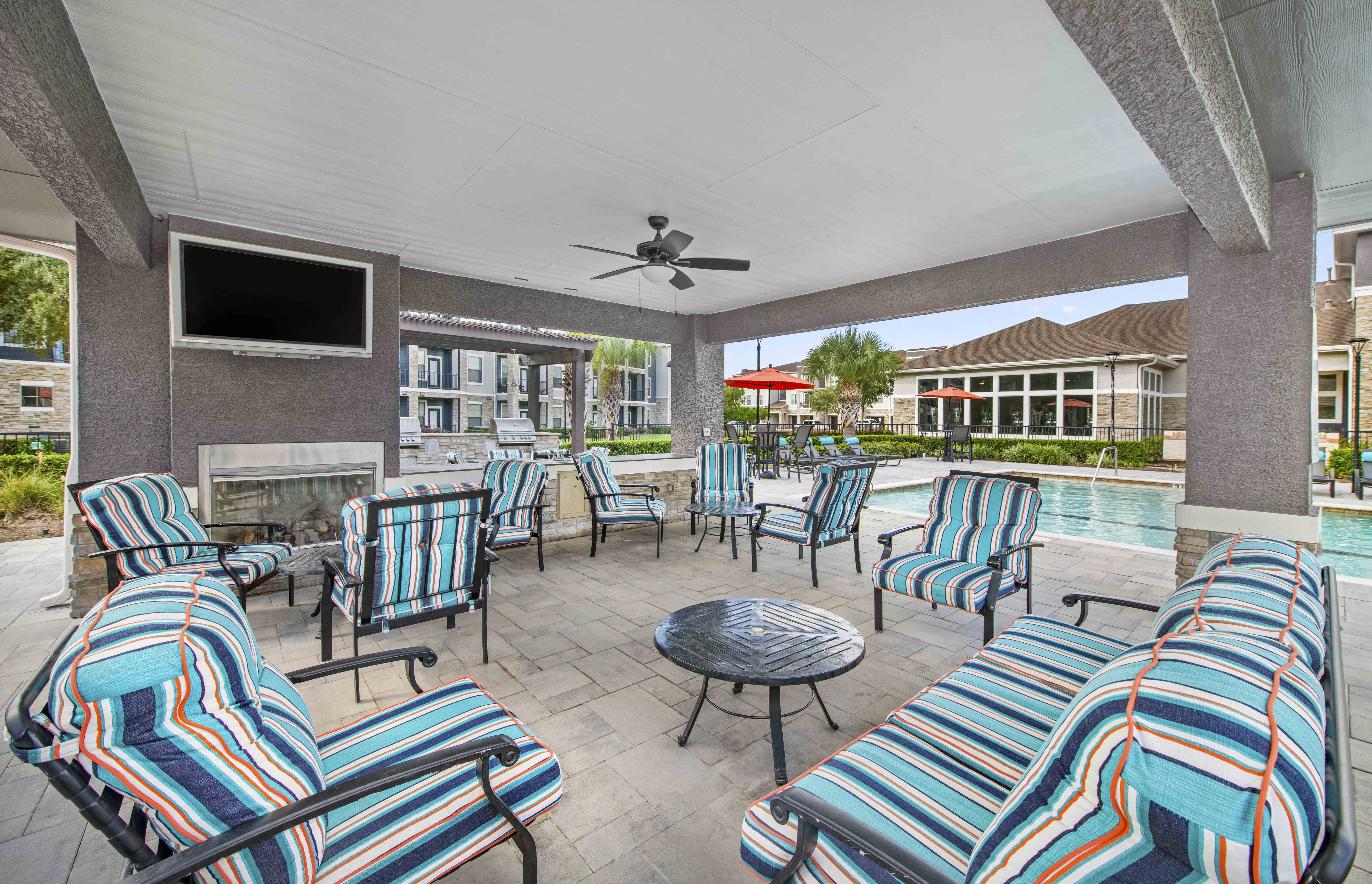 a patio with a pool and chairs and a tv