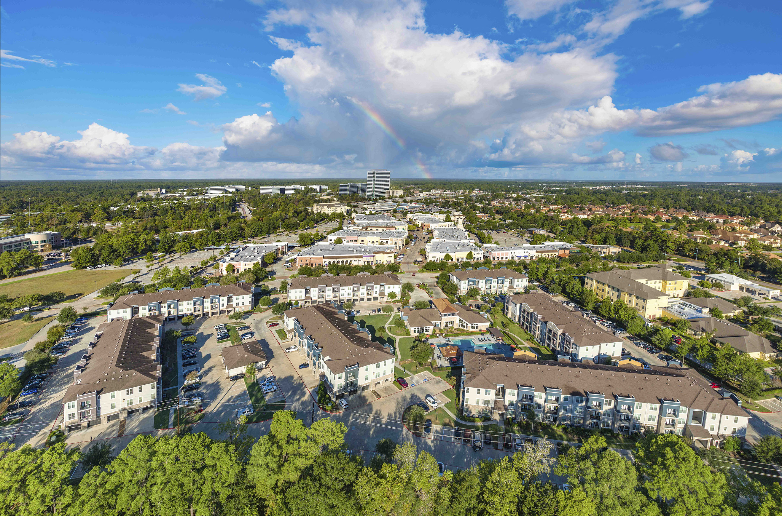 an aerial view of a city with a rainbow in the sky