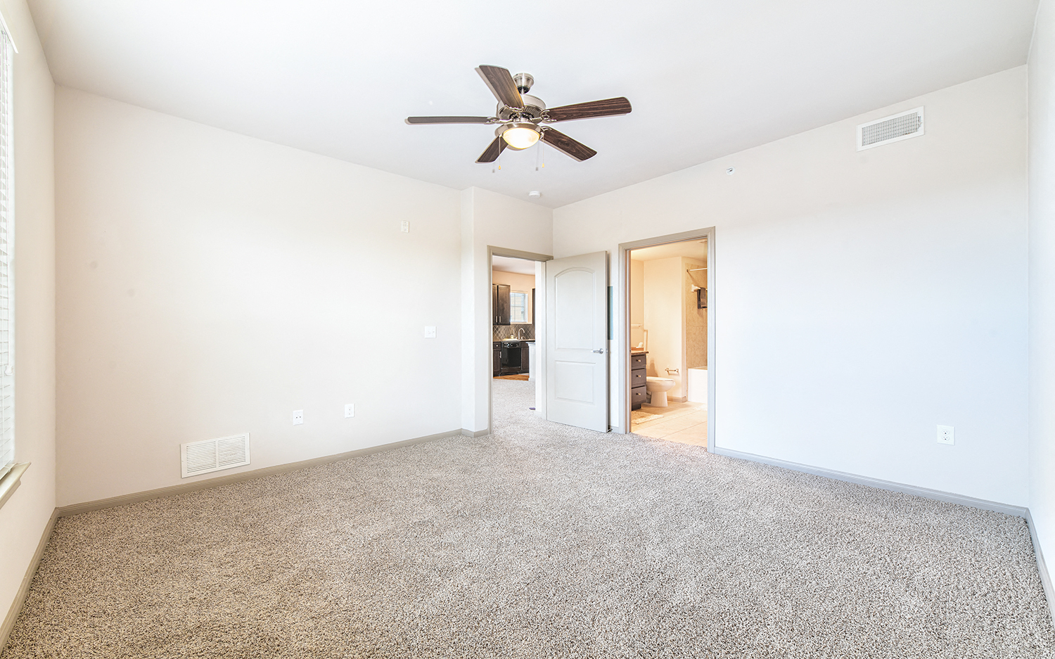 an empty living room with a ceiling fan and carpet