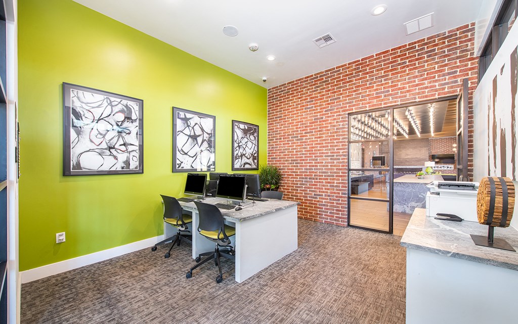 an office with green walls and a desk with two computers