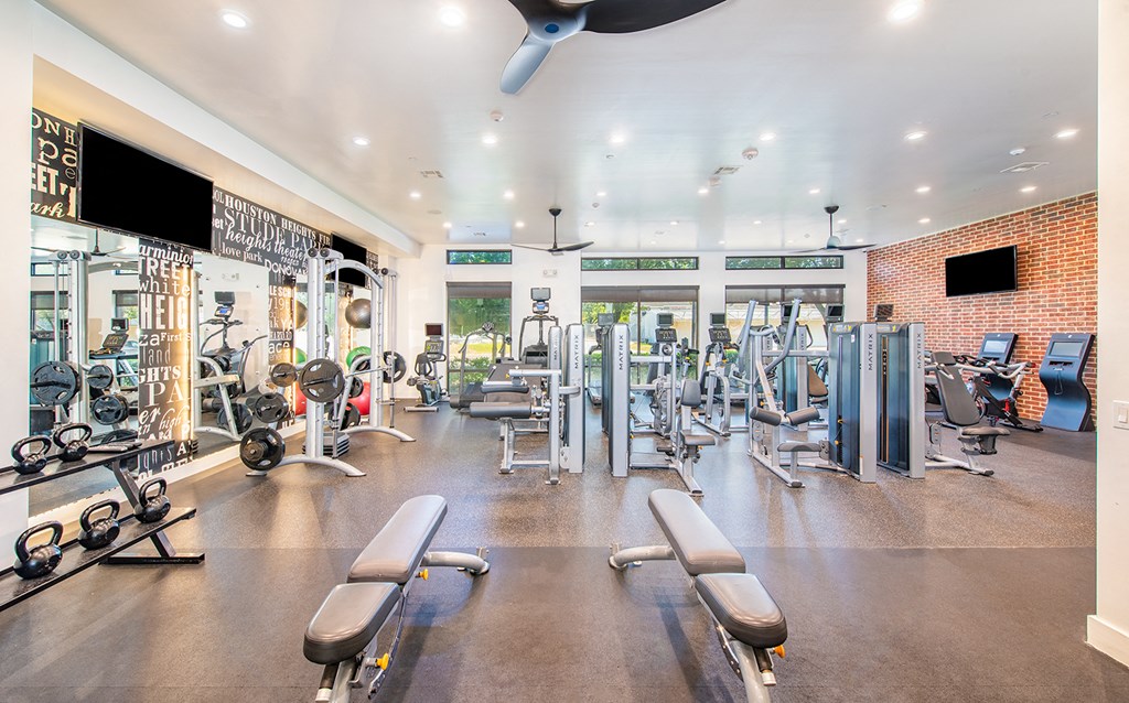 a gym with weights and cardio machines and a ceiling fan