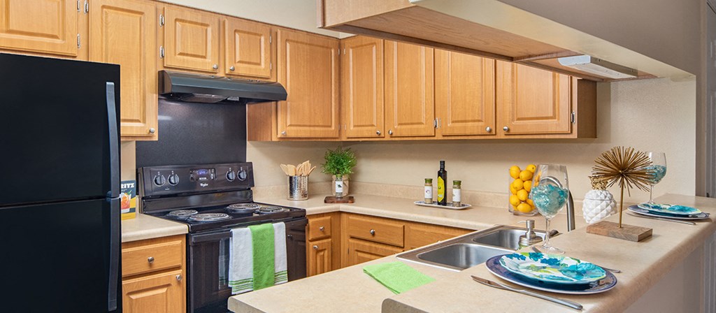 a kitchen with wooden cabinets and black appliances and a sink