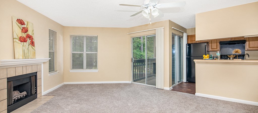 an empty living room with a fireplace and a kitchen