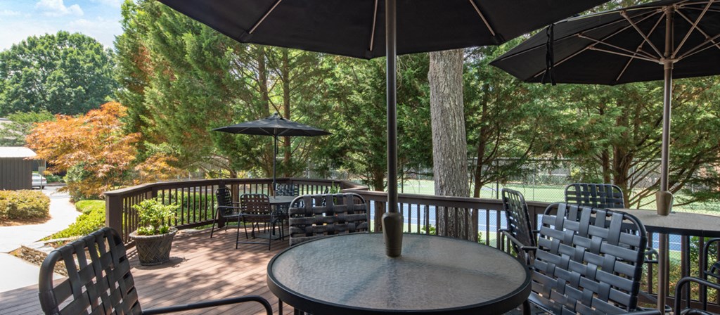a patio with tables and umbrellas overlooking a lake