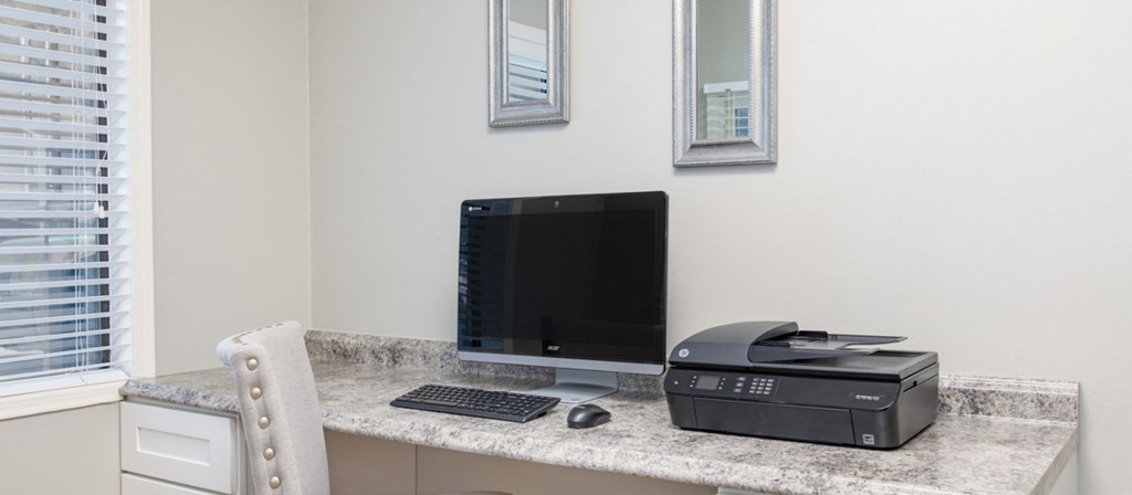a home office with a computer and printer on a granite desk